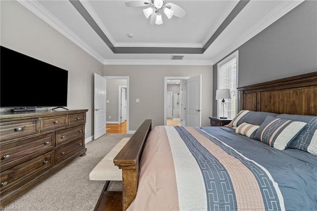 bedroom with visible vents, crown molding, a tray ceiling, and light carpet