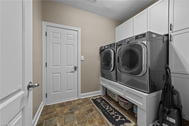 washroom with baseboards, cabinet space, stone finish floor, and independent washer and dryer