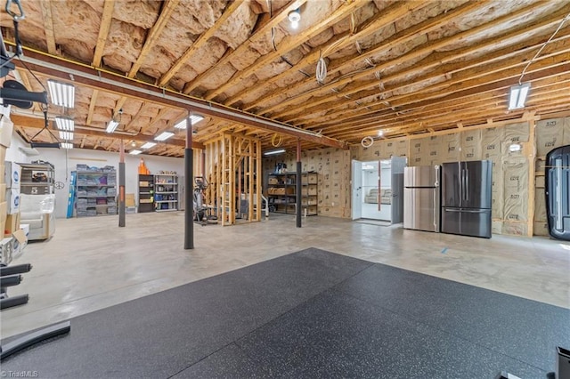 unfinished basement with freestanding refrigerator