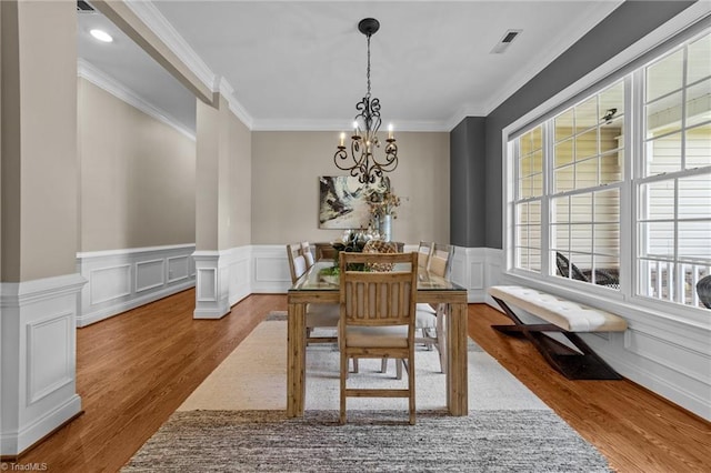 dining area with visible vents, ornamental molding, wood finished floors, and a notable chandelier