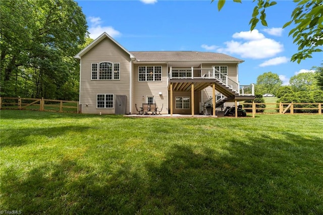 rear view of property with stairs, a fenced backyard, a lawn, and a wooden deck