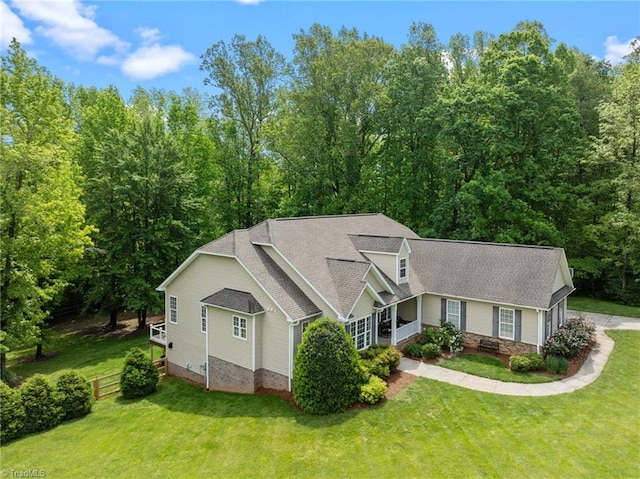 view of front of property featuring a shingled roof, a front lawn, and stone siding