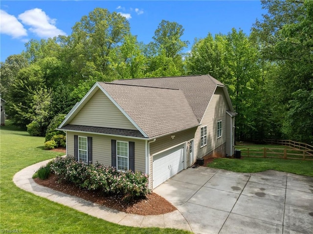 view of home's exterior featuring driveway, roof with shingles, fence, a yard, and an attached garage