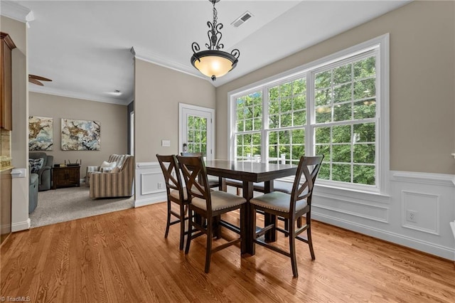dining area with crown molding, plenty of natural light, light wood finished floors, and visible vents