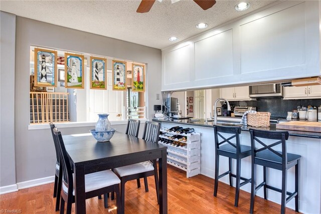 dining space featuring baseboards, recessed lighting, ceiling fan, light wood-style floors, and a textured ceiling