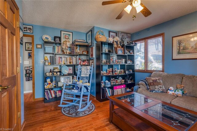 living room with a textured ceiling, wood finished floors, and ceiling fan