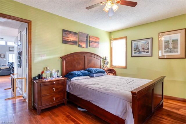 bedroom featuring dark wood-style floors, a textured ceiling, and baseboards