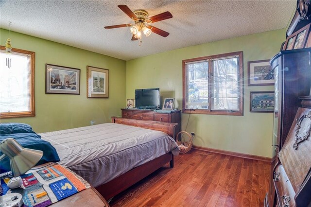bedroom featuring baseboards, a textured ceiling, wood finished floors, and a ceiling fan