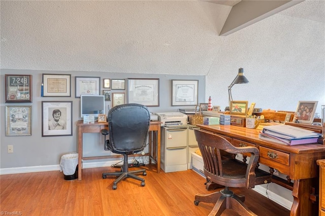 office featuring baseboards, light wood finished floors, and a textured ceiling