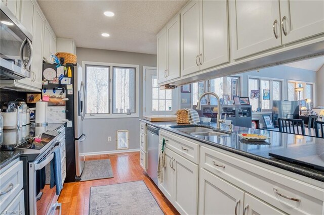 kitchen with a sink, recessed lighting, appliances with stainless steel finishes, white cabinets, and light wood finished floors