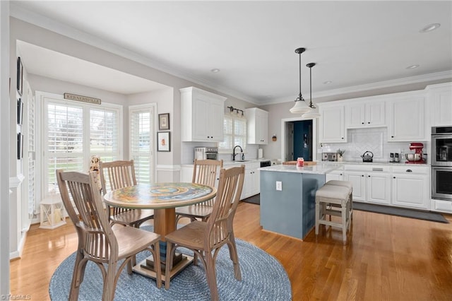 dining room featuring ornamental molding, light hardwood / wood-style floors, and sink