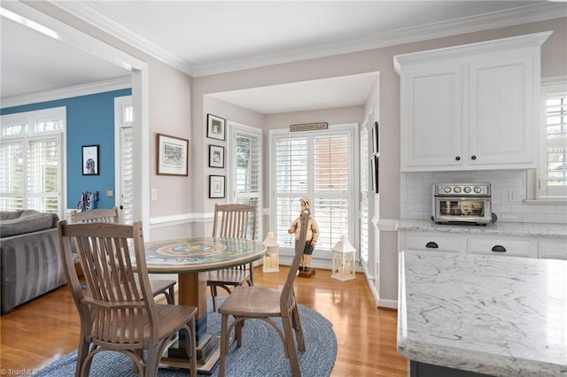 dining space featuring crown molding and light hardwood / wood-style flooring