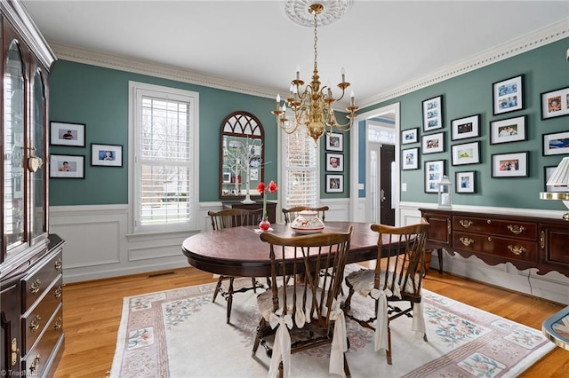 dining room featuring crown molding, light hardwood / wood-style floors, and a notable chandelier