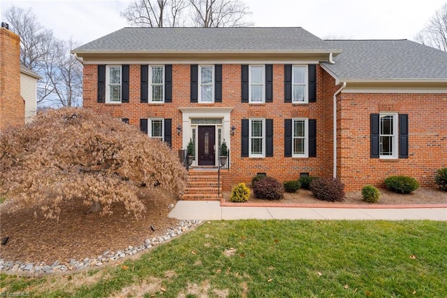 colonial-style house featuring a front lawn