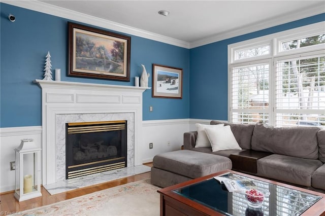 living room featuring crown molding, a high end fireplace, and light wood-type flooring