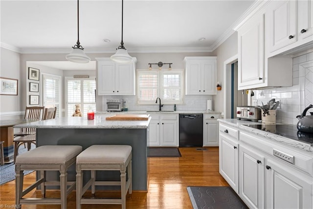 kitchen featuring a breakfast bar, a center island, black appliances, white cabinets, and decorative light fixtures