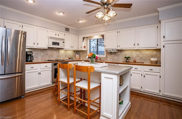 kitchen featuring white cabinetry, a center island, stainless steel fridge, and ornamental molding