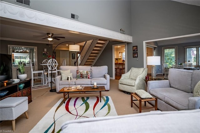 living room with ornamental molding, plenty of natural light, carpet flooring, and a high ceiling