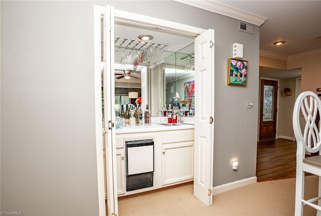 bar featuring crown molding, light colored carpet, sink, and white cabinets