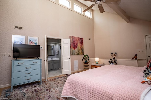 bedroom with beamed ceiling, sink, high vaulted ceiling, and ensuite bath