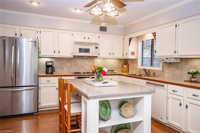 kitchen featuring sink, white cabinets, a center island, crown molding, and white appliances