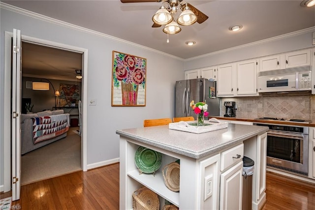 kitchen featuring a kitchen island, white cabinetry, decorative backsplash, ornamental molding, and stainless steel appliances