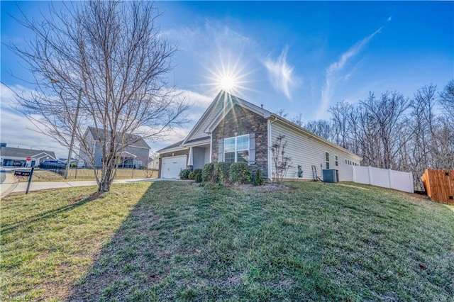 view of side of home with central AC unit, a garage, fence, stone siding, and a yard