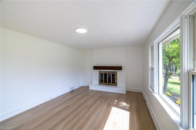 unfurnished living room with light wood-style floors, baseboards, and a brick fireplace