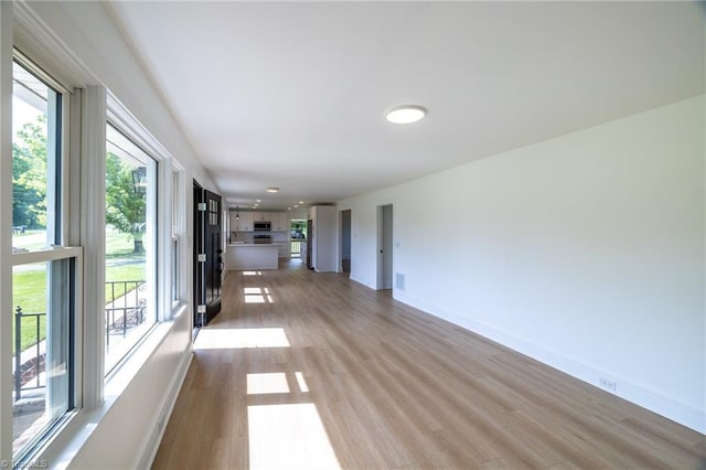 unfurnished living room with light wood finished floors and baseboards