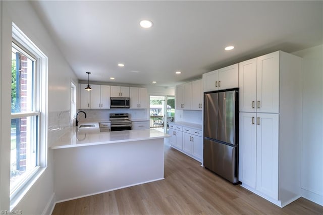 kitchen with stainless steel appliances, light countertops, white cabinets, recessed lighting, and a peninsula