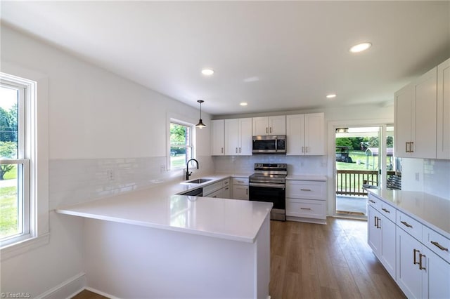 kitchen with appliances with stainless steel finishes, a sink, backsplash, light countertops, and recessed lighting