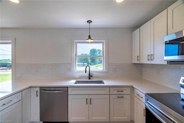 kitchen with stainless steel appliances, a sink, white cabinetry, light countertops, and backsplash
