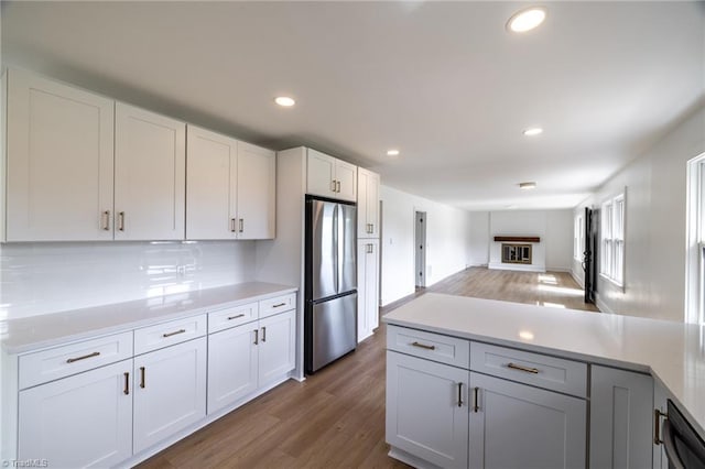 kitchen with freestanding refrigerator, wood finished floors, light countertops, recessed lighting, and decorative backsplash