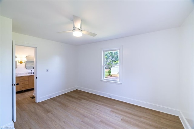 unfurnished bedroom featuring light wood-style floors, baseboards, ceiling fan, and a sink