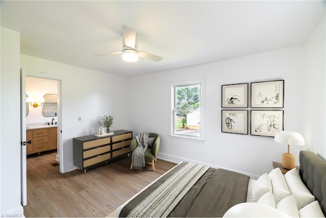 bedroom with wood finished floors, baseboards, a ceiling fan, and ensuite bathroom