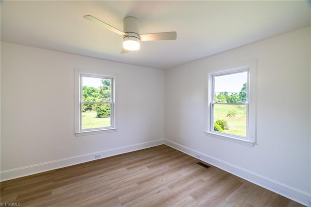 spare room featuring light wood-type flooring, baseboards, and a ceiling fan