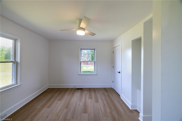 empty room with wood finished floors, baseboards, and a ceiling fan