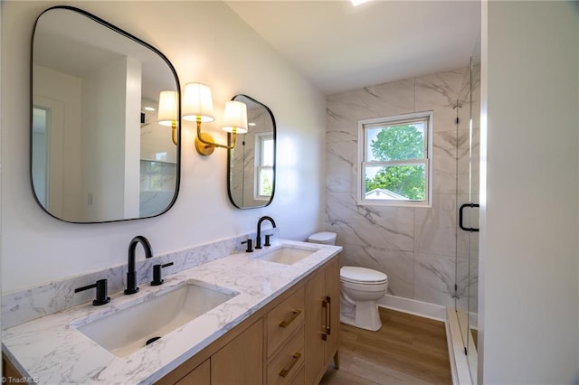 full bath featuring wood finished floors, a marble finish shower, toilet, and double vanity