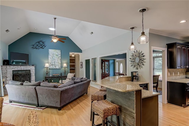 living room with a ceiling fan, light wood-style flooring, a stone fireplace, lofted ceiling, and recessed lighting