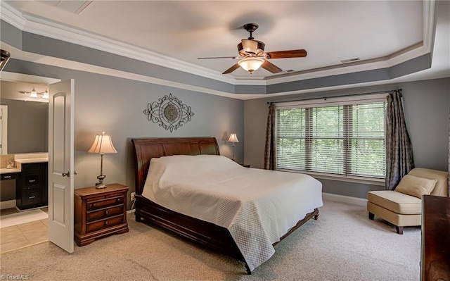 bedroom with a raised ceiling, crown molding, light colored carpet, ensuite bathroom, and ceiling fan