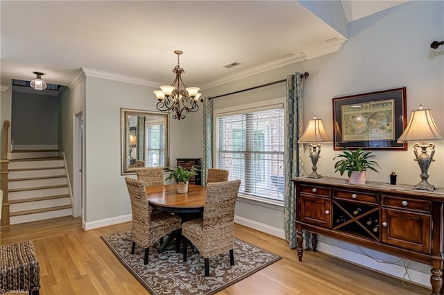 dining area featuring light wood-style flooring, a chandelier, stairway, ornamental molding, and baseboards