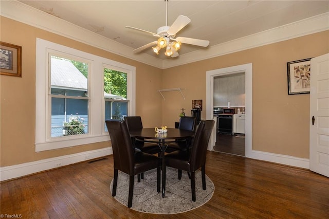 dining space featuring baseboards, dark wood-type flooring, ceiling fan, and crown molding