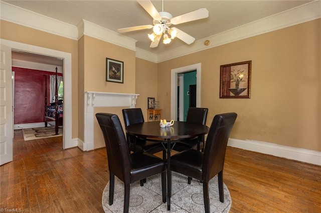 dining area featuring hardwood / wood-style floors, baseboards, a ceiling fan, and ornamental molding