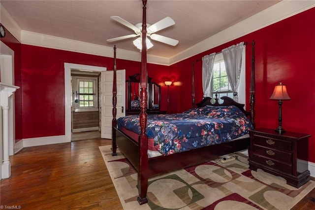 bedroom featuring wood finished floors, multiple windows, baseboards, and crown molding