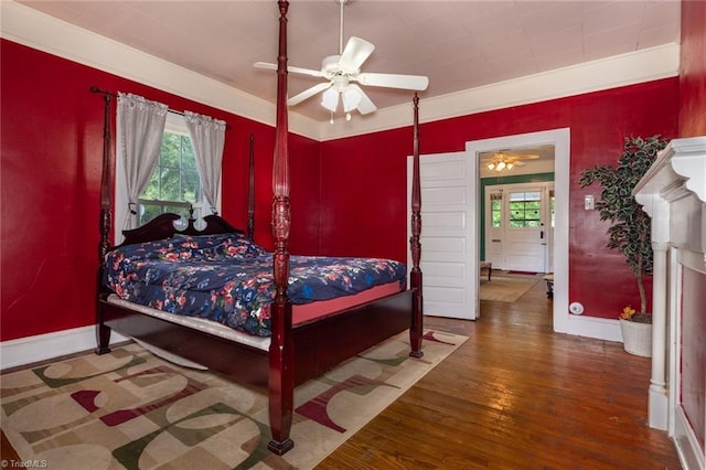 bedroom with wood finished floors, multiple windows, baseboards, and a ceiling fan