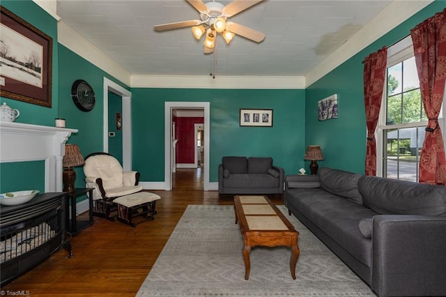 living room featuring ceiling fan, wood finished floors, crown molding, and baseboards