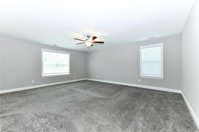 unfurnished room featuring dark colored carpet, a ceiling fan, and baseboards