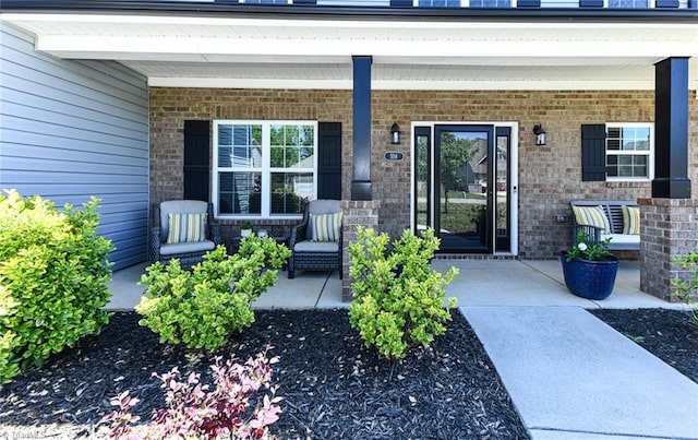 entrance to property featuring a porch and brick siding
