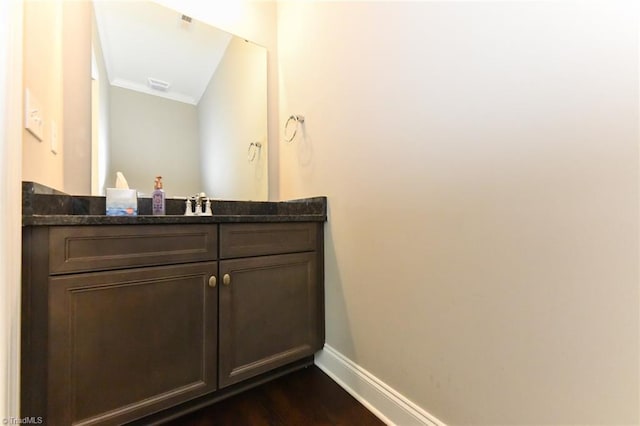 bathroom with baseboards, ornamental molding, vanity, and wood finished floors