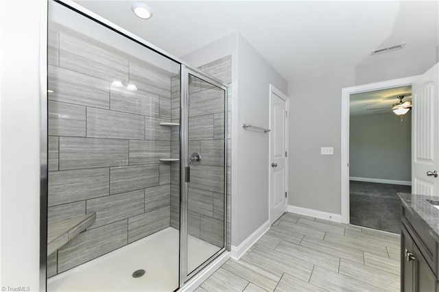 bathroom with visible vents, vanity, baseboards, ceiling fan, and a shower stall